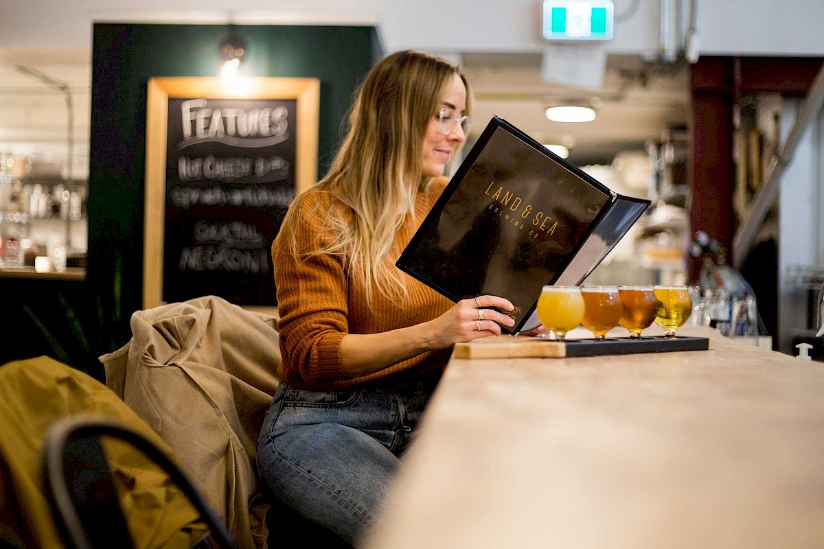Girl sitting at a bar with a tasting flight of beer